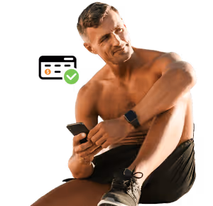 Man in black shorts holding phone and wearing smartwatch, seated with a focused expression.